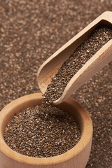 Organic natural chia seeds, wooden scoop and bowl close-up