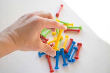 He holds a lot of colorful plastic parts of the designer in his hands. Rainbow elements in the hands. Choosing a future profession for a child. Methods of early child development