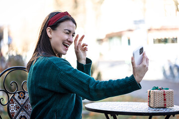 Happy young woman taking a selfie, preparing for the holiday of Christmas.