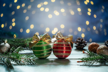 Green and red Christmas bulbs with golden bows, fir tree branches and ornaments on wooden...