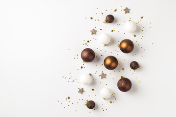 Top view photo of brown white and golden christmas tree decorations balls shiny stars and sequins on isolated white background with copyspace