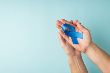 First person top view photo of male hands holding blue silk ribbon in palms symbol of prostate...