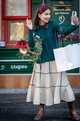 Happy young woman taking a selfie, preparing for the holiday of Christmas.