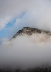 Epic mountain landscape image of Pen Yr Ole Wen in Snowdonia National Park with low cloud on peak and moodyfeel