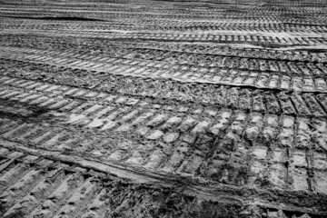 abstract black and white image of tire tracks of construction vehicles in sand on a construction...
