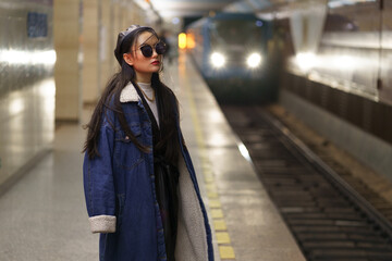 Stylish korean girl in eyeglasses and street fashion outfit at underground platform with...