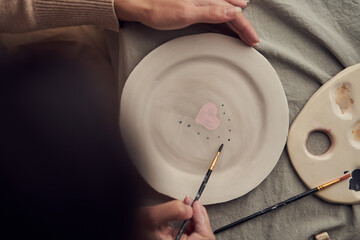 Crop female painting heart on plate