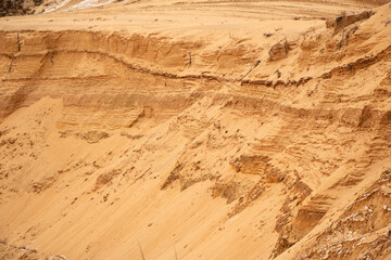 Textural sand, with  relief surface, multi-colored layers and different in size of granules, in outdoor sand career, after mining ore and sand for construction.