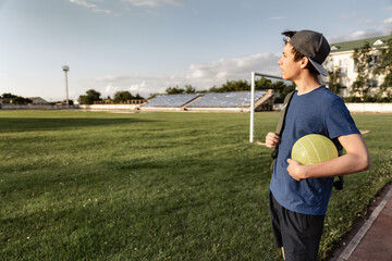 concept of sports and health - teen boy posing at a stadium, a soccer field with green grass.