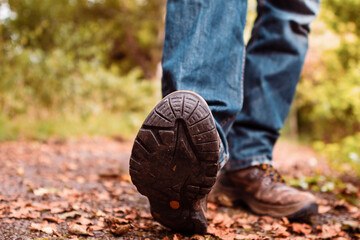 Old brown worn out hiking boots and blue jeans in a park. Selective focus. Outdoor adventure concept. Rugged lasting design.