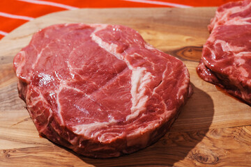Two rib eye steaks on a wooden cutting board. Premium beef product. Fresh meat. Butcher craft and food supply industry.