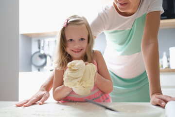 Little girl shows the dough and smiles