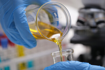Yellow liquid is pouring into a measuring vessel