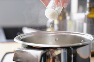 Woman prepares food in a saucepan and salt