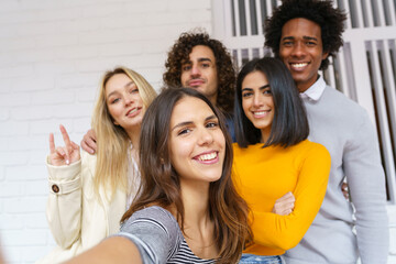 Obraz premium Multi-ethnic group of friends taking a selfie together while having fun outdoors.