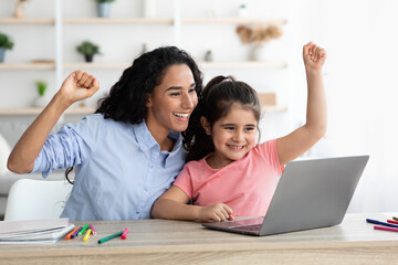 Overjoyed Mother And Little Daughter Celebrating Success With Laptop At Home