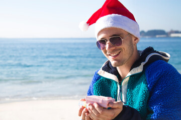 Obraz premium man with christmas santa claus hat holding gift packages