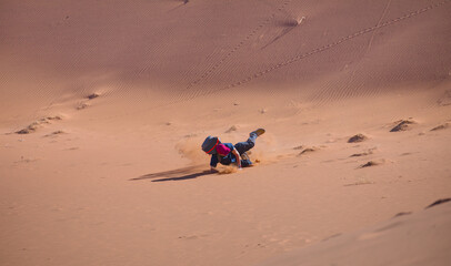 A man falling on the sand while climbing up the hill - Dead Vlei in Namib desert, peoples climbing to top of dune, Namibia, Southern Africa landscape