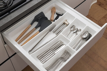 Utensils in white kitchen drawer. kitchenware for cooking. Kitchen modern interior detail. top view
