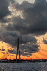 Magnificent sunset over the Daugava river and the Vansu or Suspension bridge in Riga, Latvia. Colorful clouds and warm skylight