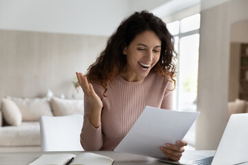 Overjoyed surprised businesswoman reading good unexpected news in letter, working with...