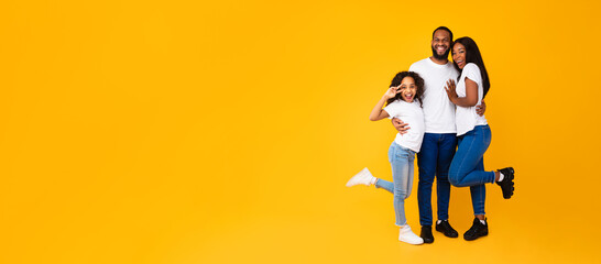 African American man hugging his wife and excited daughter