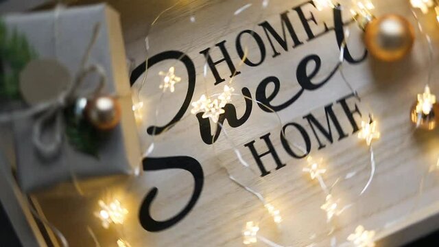 Home sweet home - the inscription spinning on the board in the Christmas decor, fairy lights,a box with a gift for the new year. Rotating background