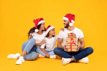 Arab Family Holding Christmas Gifts Boxes Over Yellow Studio Background