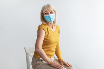 Mature Lady In Face Mask Showing Vaccinated Arm, Gray Background