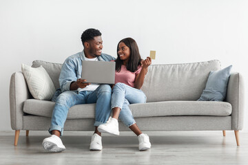 Obraz na płótnie Canvas Black couple using pc and credit card at home