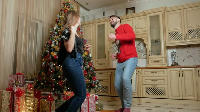 Couple dance near christmas tree with a lot of gifts in the kitchen. High quality FullHD footage