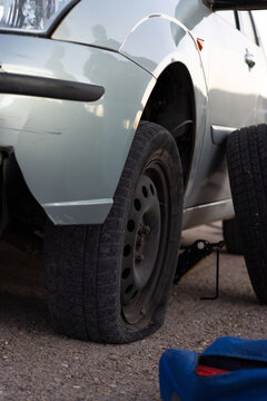 vertical detail image of a car with a flat tire about to have the tire changed