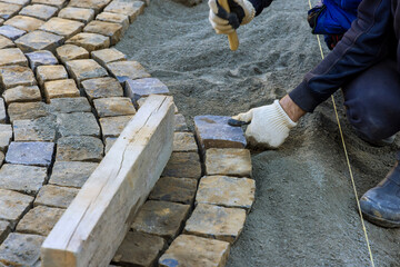 Laying granite cubes stone pavement on the a city street with construction worker