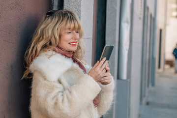 middle-aged woman on the street with mobile phone and coat