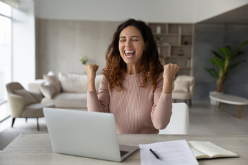 Overjoyed emotional businesswoman showing yes gesture, using laptop, celebrating success, excited...