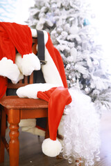 Santa costume hanging in white room. Chair with clothes from Santa Claus