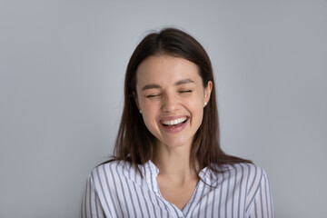 Close up head shot overjoyed young woman laughing, showing positive emotions, isolated on white studio background. Happy dental clinic patient demonstrating perfect smile with straight white teeth.