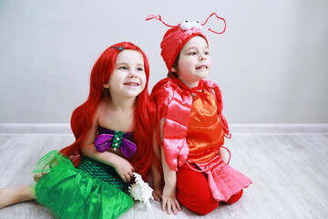 Children in smart carnival costumes on a plain background. Costume of sea fairy creatures. Mermaid and crab.