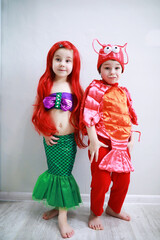 Children in smart carnival costumes on a plain background. Costume of sea fairy creatures. Mermaid and crab.