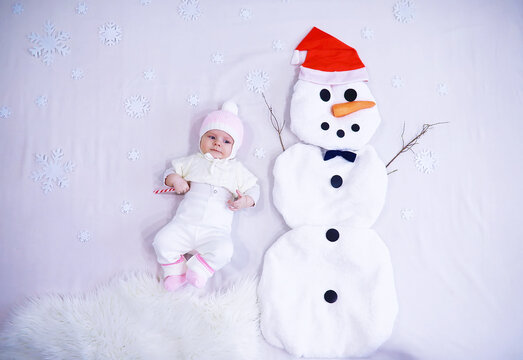 Newborn baby on a white background. Painting from white fabric. Snowman and baby. Christmas Holidays.