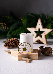 Obraz na płótnie Canvas White advent candle on wooden box with christmas lights, cones, wooden star. Vertical