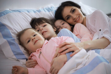 A family with children having fun on the bed under the covers during the Christmas holidays.