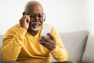 Black Man Using Smartphone Wearing Eyeglasses Having Poor Eyesight Indoor