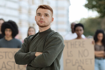 Thoughtful young man posing over multiracial group of demonstrators