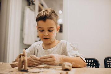 Cute boy forming toys from clay