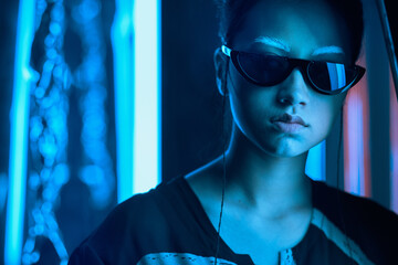 Teenage asian girl in sun glasses in neon light