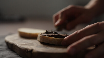 man spreading chocolate spread on ciabatta slice on dining table