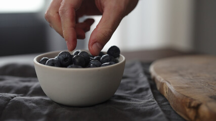 man take washed blueberries from white bowl on table