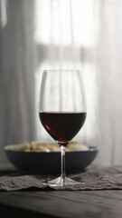 red wine into wineglass with fusilli pasta on background
