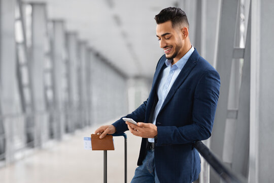 Booking Hotel Online. Young Arab Businessman Using Smartphone While Waiting In Airport